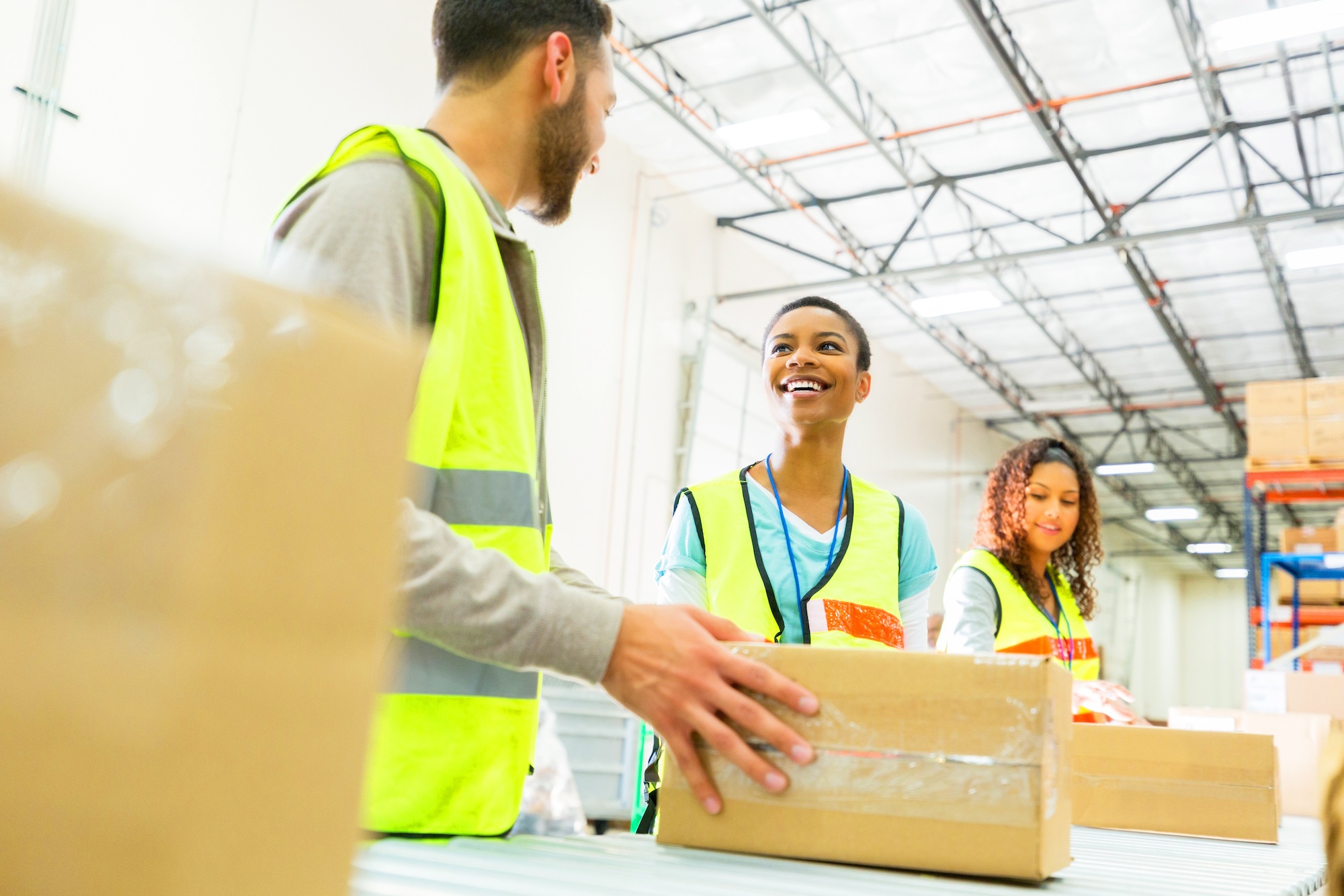Three warehouse workers talking and laughing with boxes Three warehouse workers talking and laughing with boxes